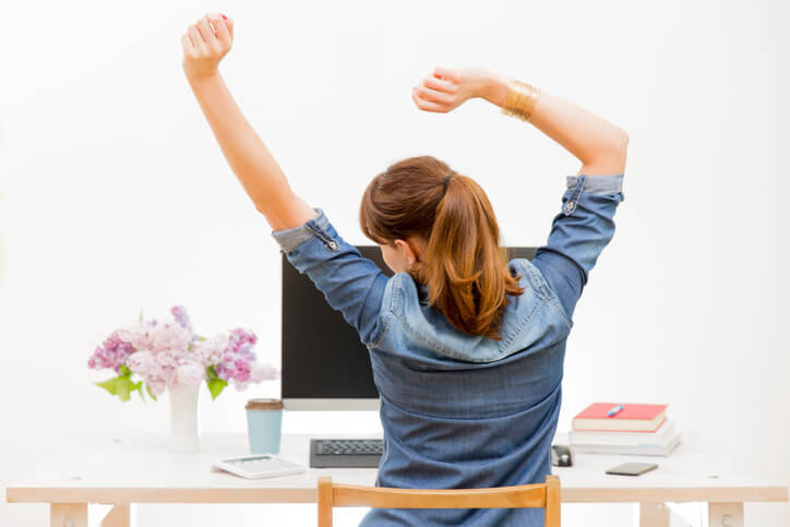 Woman stretching her arms sitting by the table at work next to computer Woman stretching her arms sitting by the table at work next to computer
